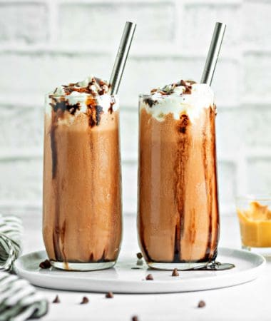 two glasses of keto chocolate peanut butter milkshake with chocolate chips scattered around