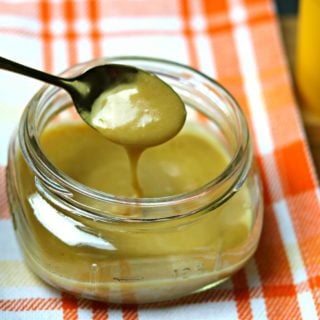 A glass jar full of Keto Browned Butter Salted Caramel with a spoon