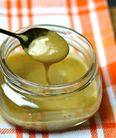 A glass jar full of Keto Browned Butter Salted Caramel with a spoon