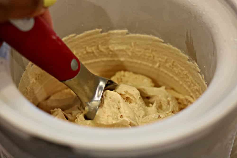 Peanut butter ice cream with a scoop inside of an ice cream maker