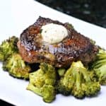 Ranch spiced steaks on top of a bed of broccoli on a white serving dish