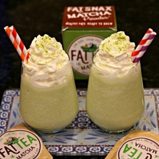 Two glasses of Keto Matcha (Green Tea) Creme Frappuccinos with red and white straws, and surrounded by Fat Snax products