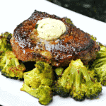 Top sirloin steak with melted butter on a plate with roasted broccoli.