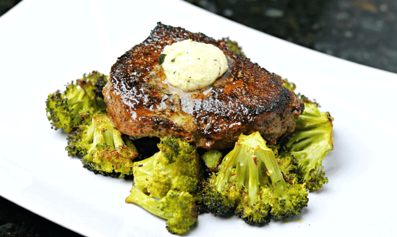 Top sirloin steak with melted butter on a plate with roasted broccoli.