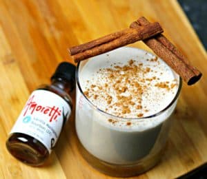 Keto Coquito in a glass cup with cinnamon sticks