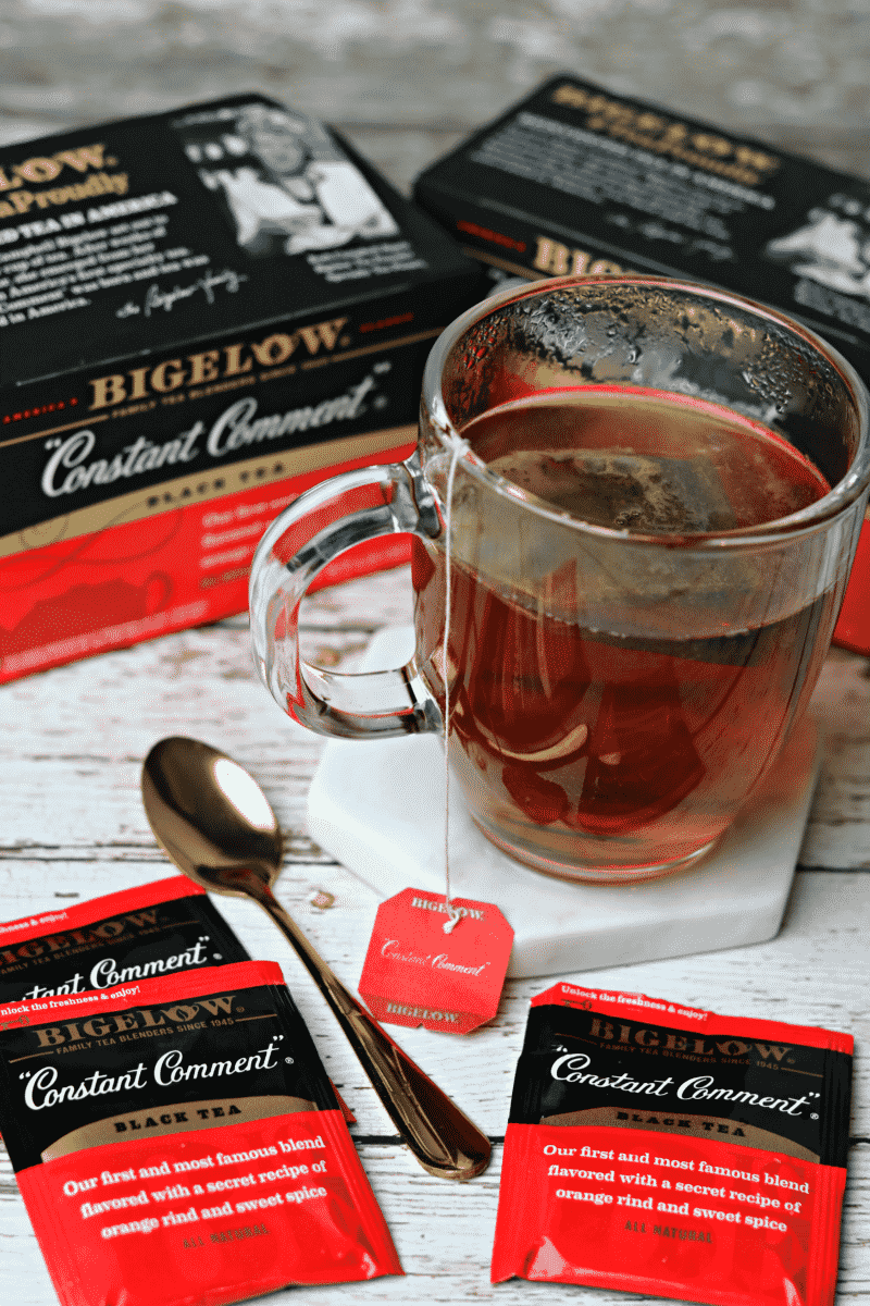 Two boxes of Bigelow Constant Comment Tea with a glass of tea and a golden spoon