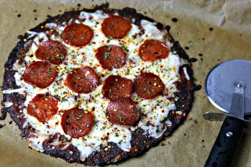 Easy Keto Pepperoni pizza using a pre-made cauliflower pizza crust on parchment paper.