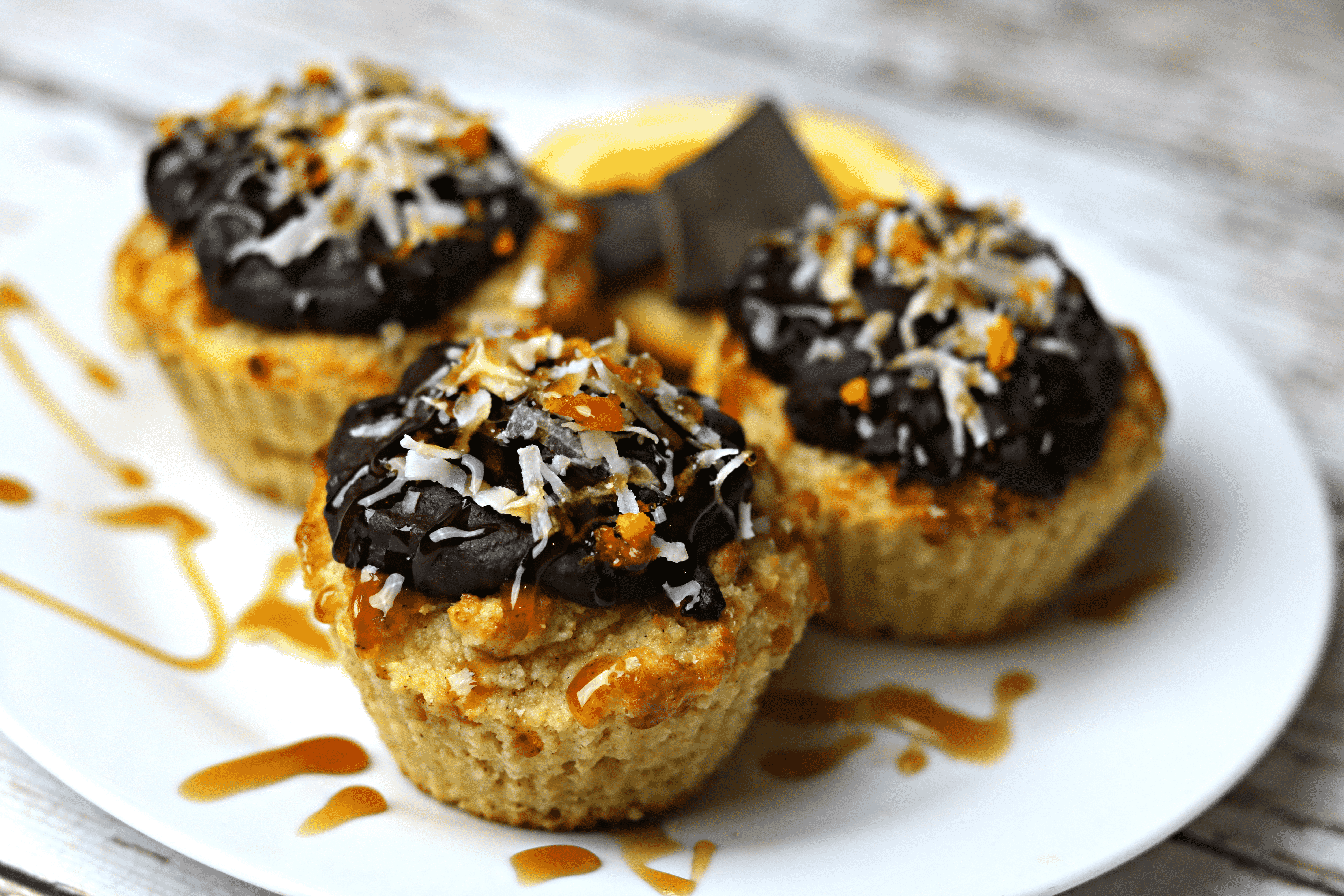 Three Keto Orange Muffins with Orange Chocolate Glaze on a white plate