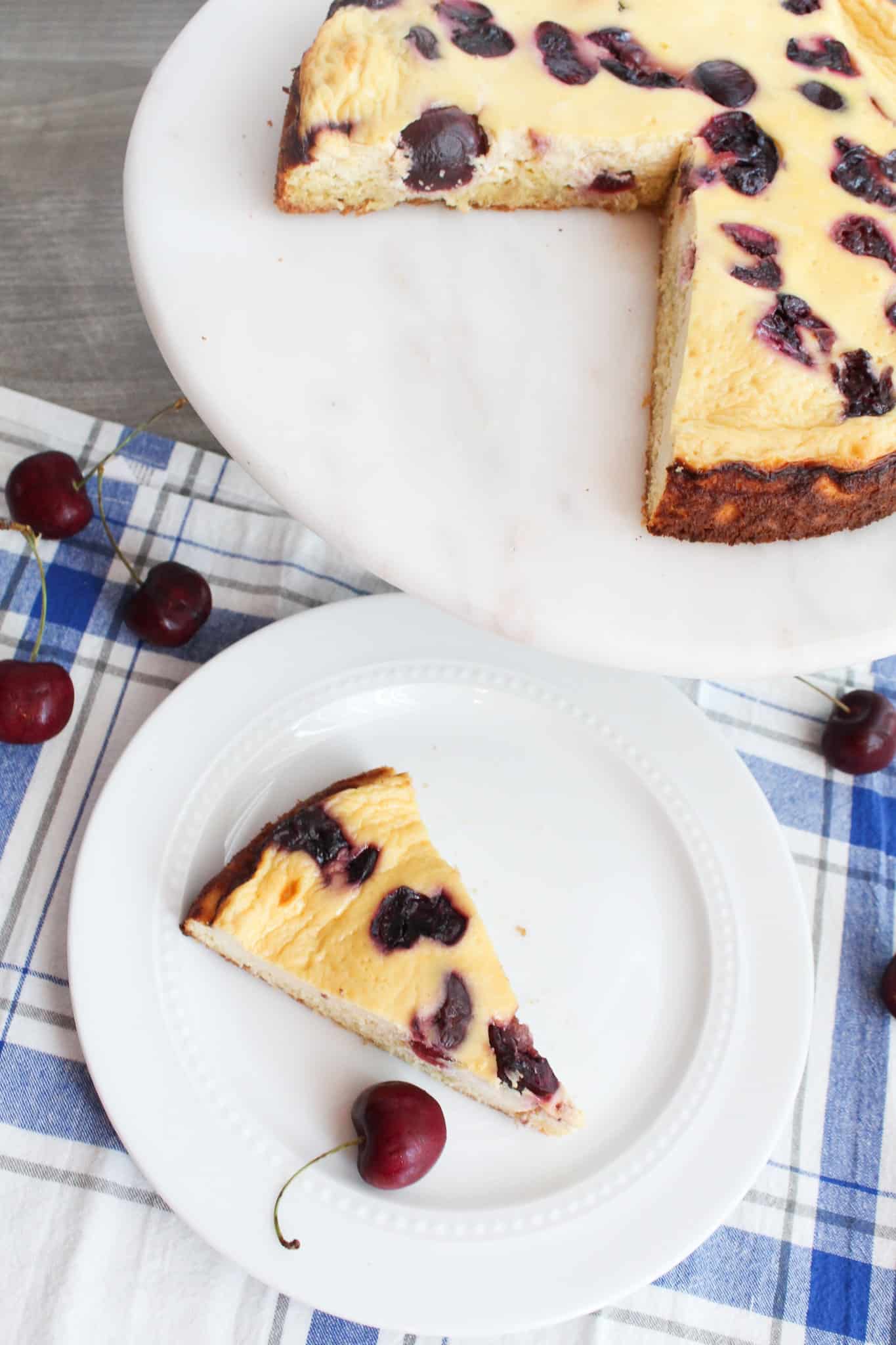 Two slices of Sugar-free Sour Cream Cake with cherries on two white serving dishes