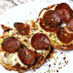 Two keto and low-carb pizza halves sitting on a white plate