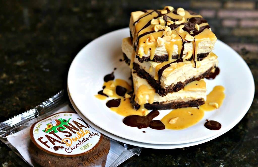 Keto Snickers Cheesecake recipe on a plate with a Fat Snax Double Chocolate cookie