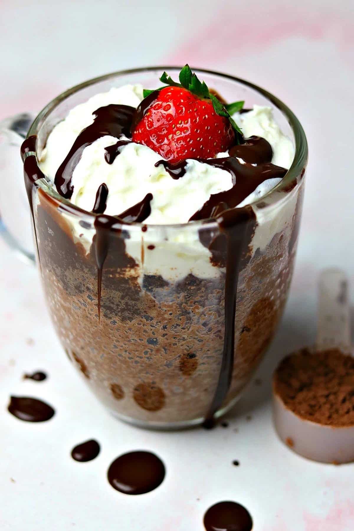 keto chocolate mug cake in a glass mug with sugar free whipped cream and a strawberry