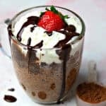 keto chocolate mug cake in a glass mug with a scoop of chocolate powder