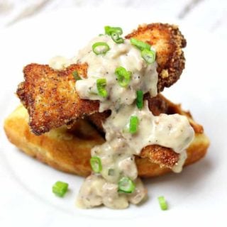 Dairy-free, Gluten-free Chicken & Waffles on a white plate topped with sausage gravy