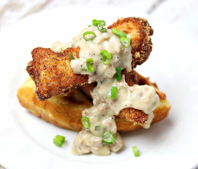 Dairy-free, Gluten-free Chicken & Waffles on a white plate topped with sausage gravy