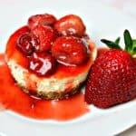 Gluten-free keto cheesecake on a white plate with strawberry sauce on top