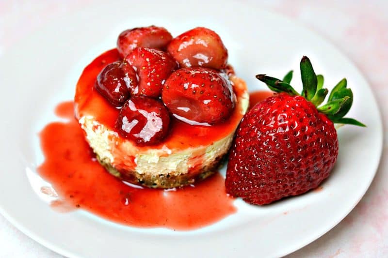 Gluten-free keto cheesecake on a white plate with strawberry sauce on top