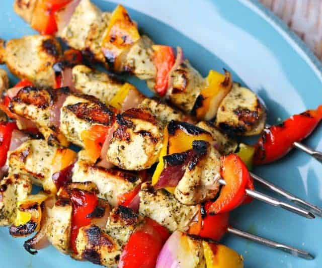 A stack of chicken kabob skewers on a blue serving dish.