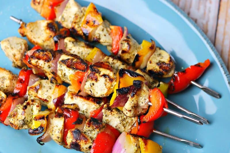 A stack of chicken kabob skewers on a blue serving dish.