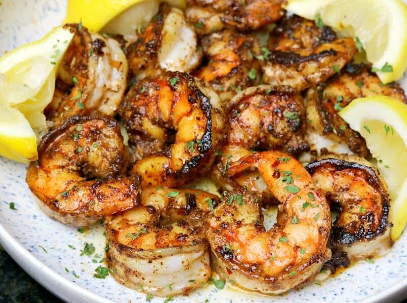 close-up of pan-seared shrimp in a bowl with lemons