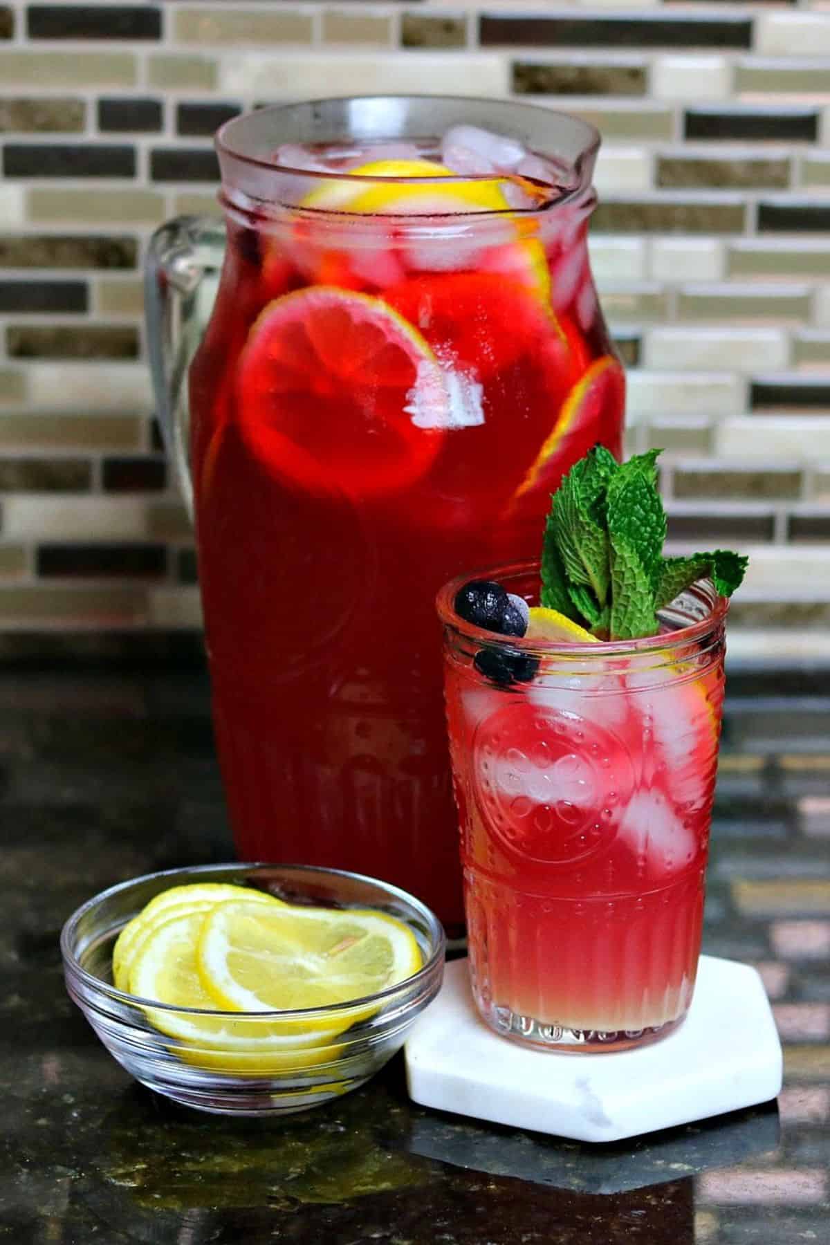 a glass of keto blueberry iced tea lemonade with a pitcher