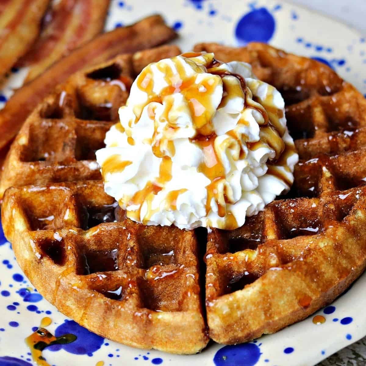 keto waffles on a plate with sugar free whipped cream and bacon