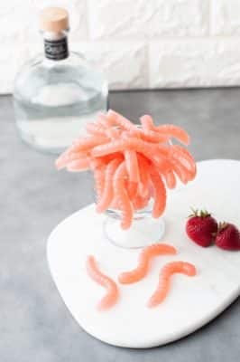 Keto Margarita Gummy Worms with strawberries on a white serving dish