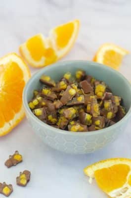 Orange Chocolate Keto Candy in a light blue bowl surrounded by slices of oranges
