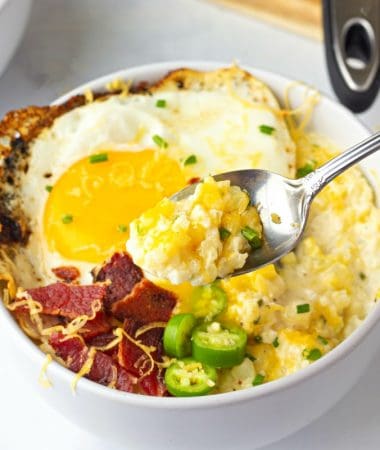 A bowl of food with Cheesy Cauliflower, an egg, jalapeño, and crispy bacon