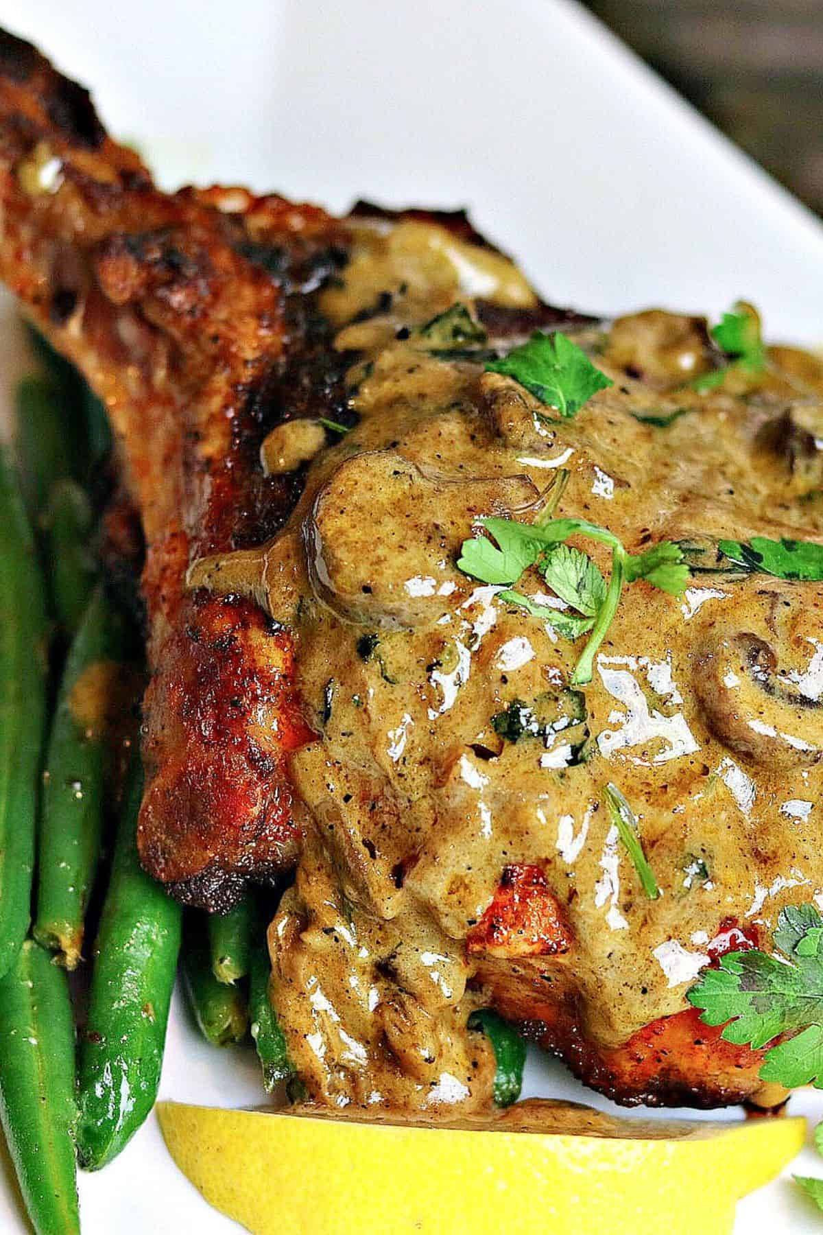 bone-in pork chop on a plate with mushroom cream sauce dripping down