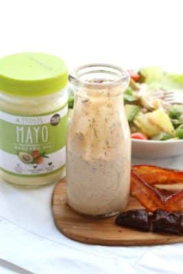 A jar of Paleo Chipotle Bacon Ranch Dressing next to Primal Kitchen Mayo and a bowl of salad