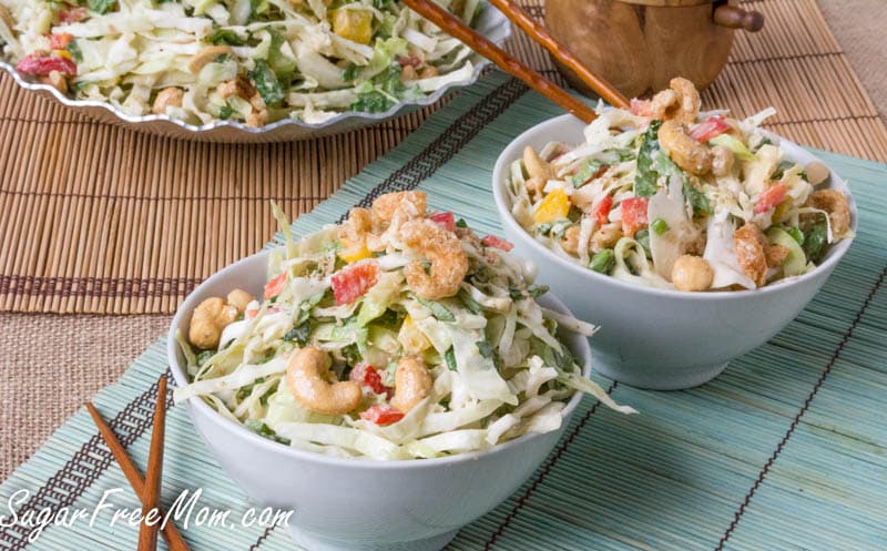 Two small white bowls of salad garnished with cashews