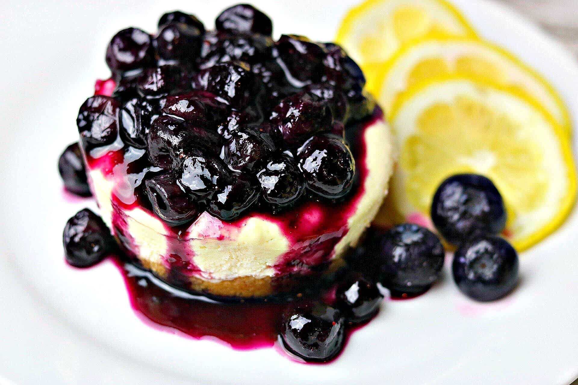 Lemon Blueberry Cheesecake Bites on a white plate with lemon slices