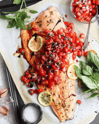 Bruschetta Salmon covered in cherry tomatoes and three slices of lemon 