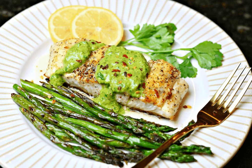 Halibut on a plate with asparagus and chimichurri sauce