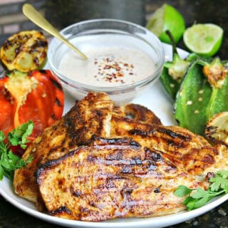 grill pan chicken breast on a plate with vegetables and limes