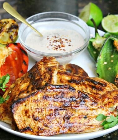 grill pan chicken breast on a plate with vegetables and limes