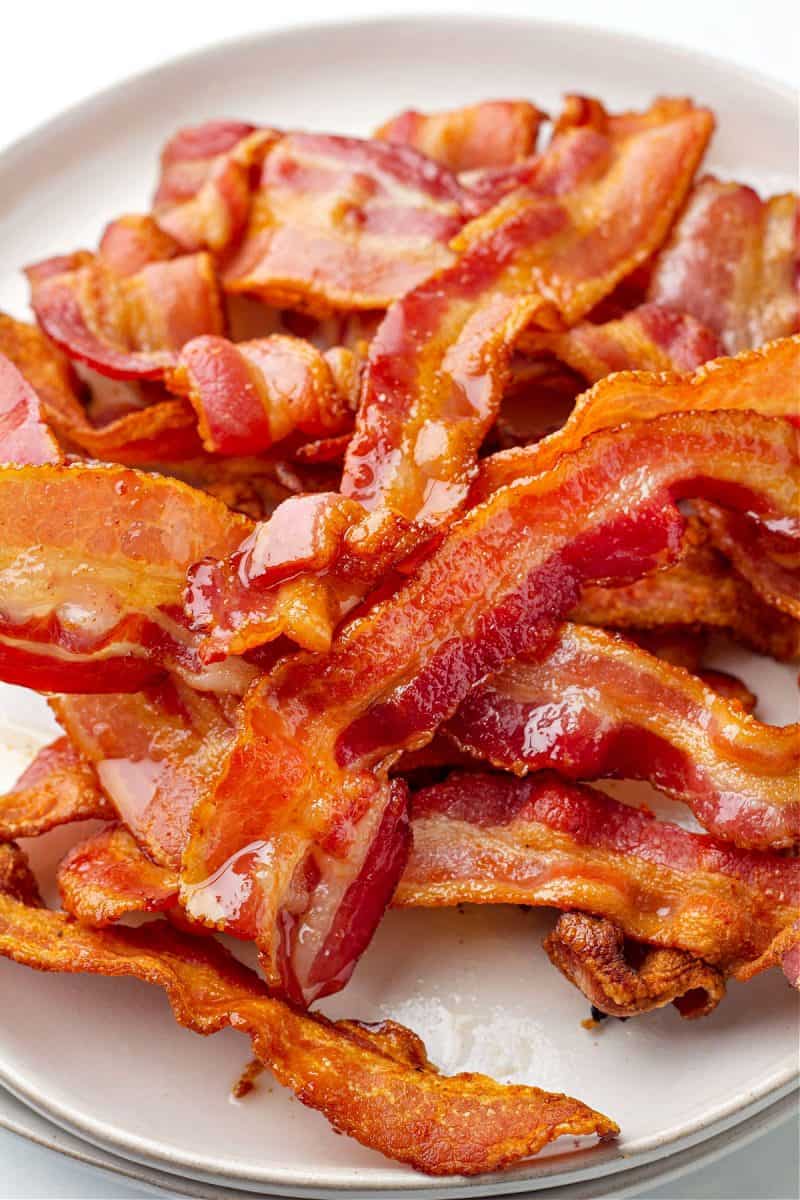 a plate filled with a pile of cooked bacon