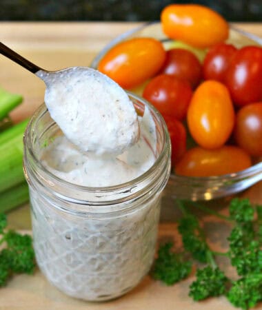ranch dressing in a glass jar with parlsey, celery. and cherry tomatoes in separate bowls