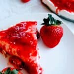 A slice of no-bake cheesecake with strawberry topping on white plate