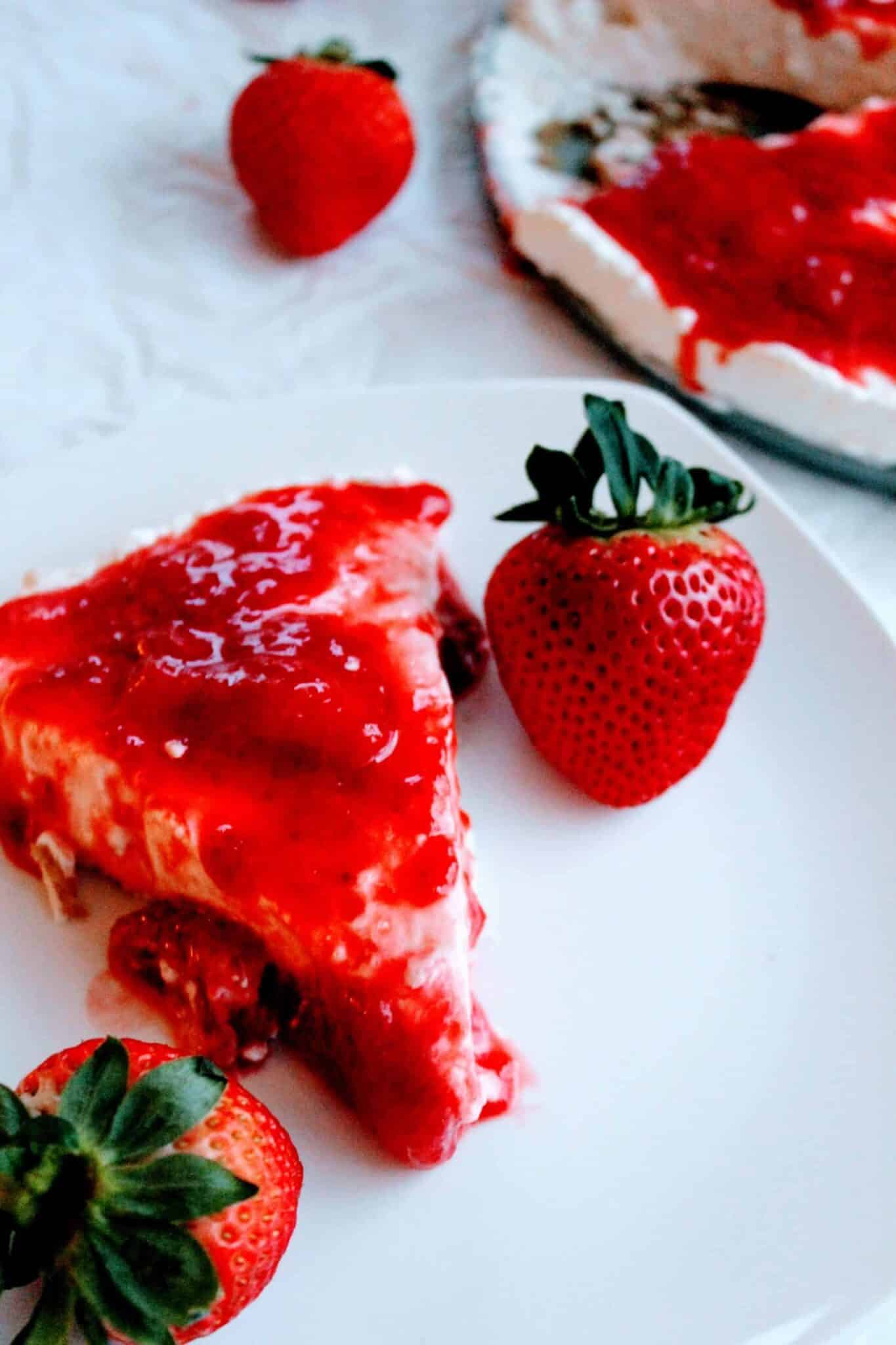 A slice of no-bake cheesecake with strawberry topping on white plate