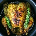 a whole chicken in a Ninja foodi pressure cooker with rosemary sprigs on top