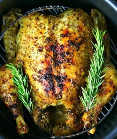 a whole chicken in a Ninja foodi pressure cooker with rosemary sprigs on top