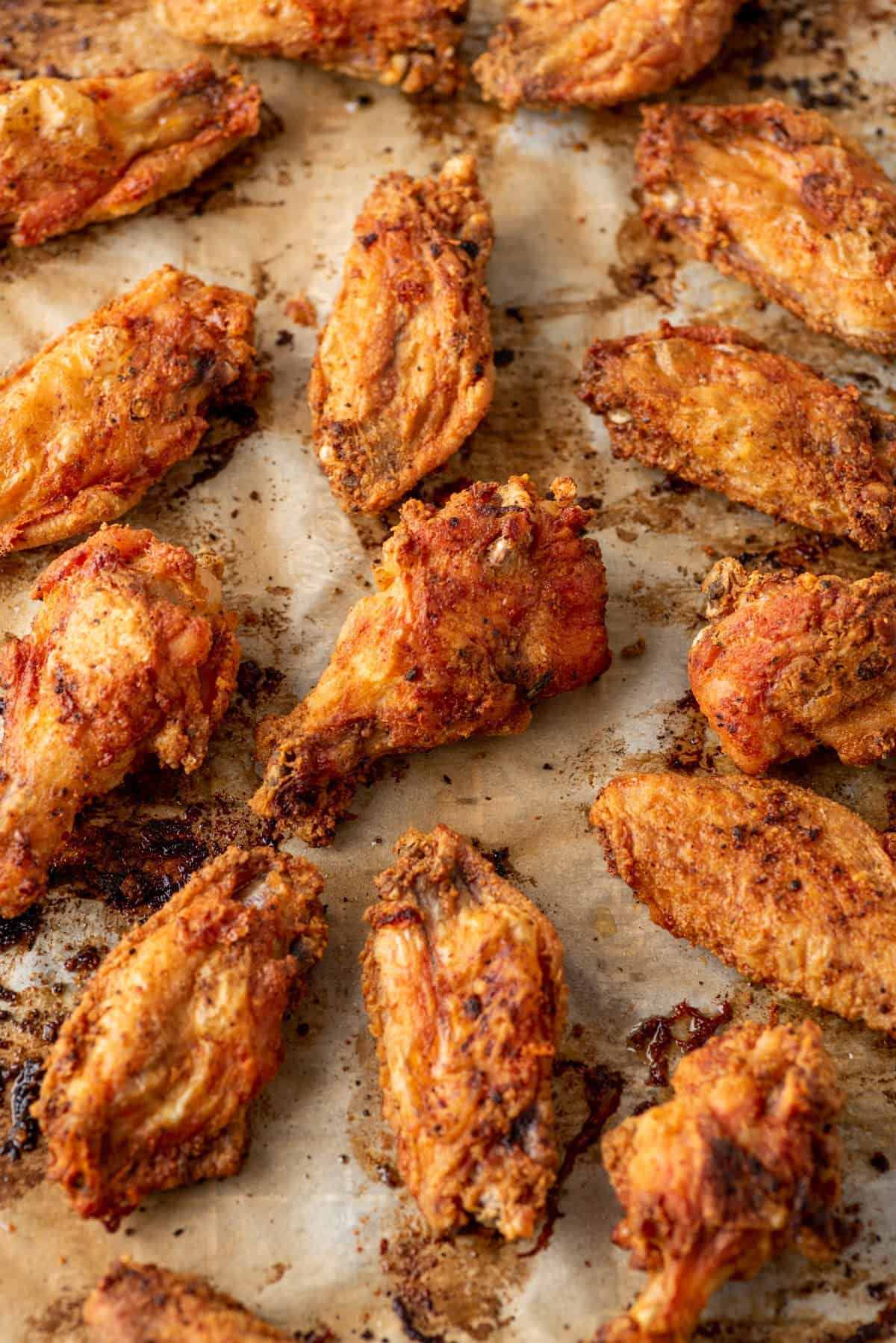 Baked chicken wings on a baking sheet covered in parchment paper