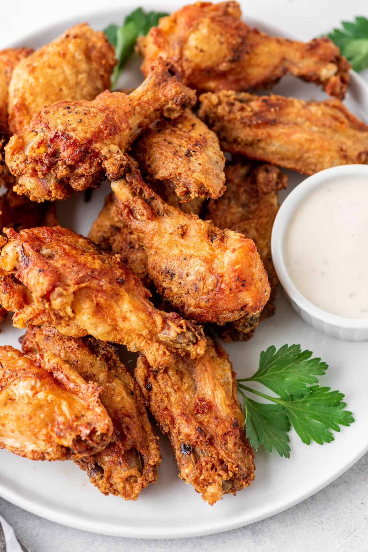 A plate of wings with a garnish of parsley and a ramekin of ranch