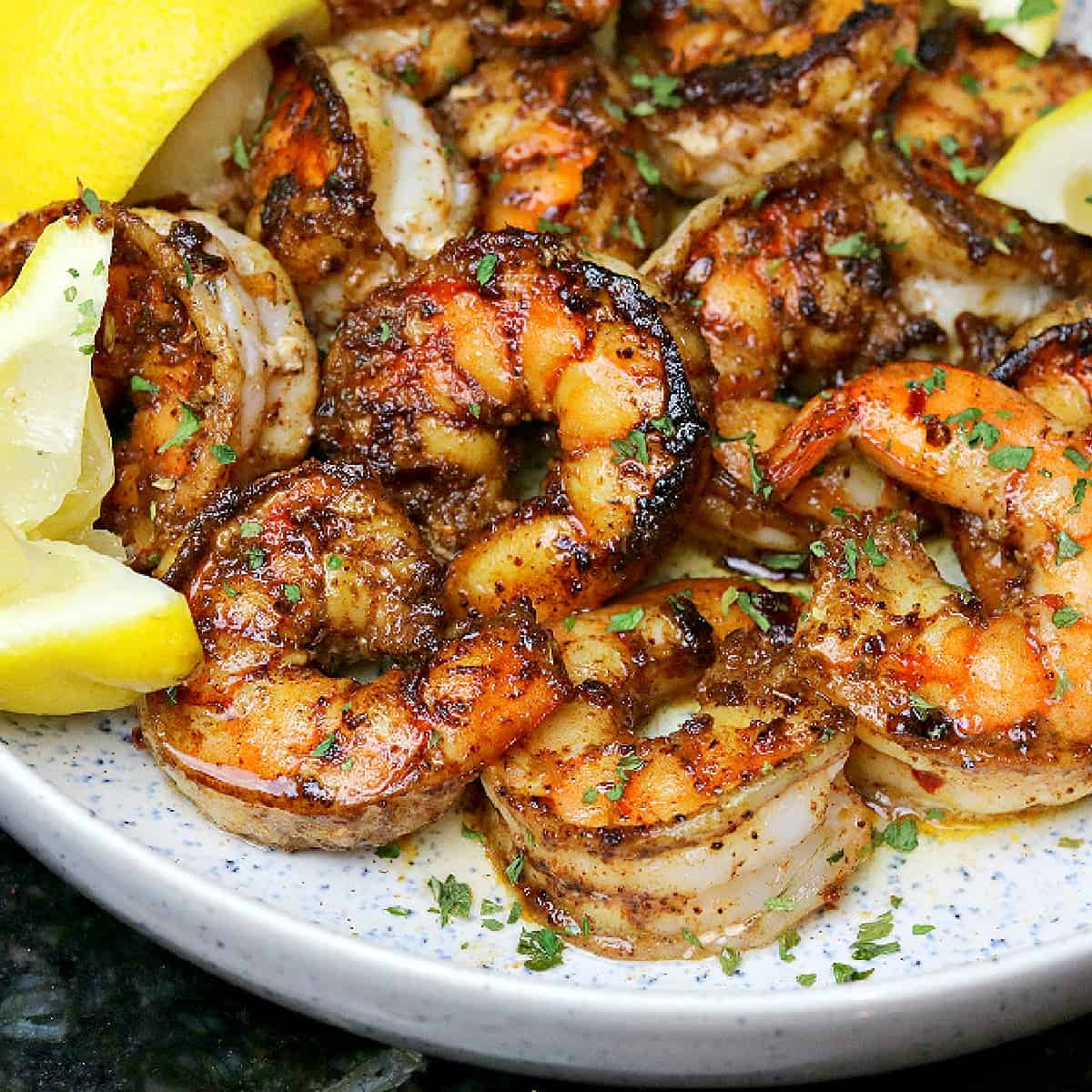 pan seared shrimp in a bowl with lemon wedges