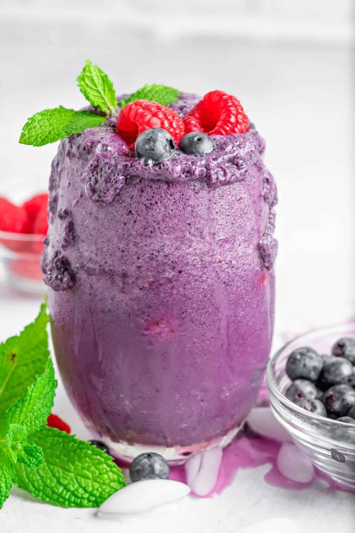 one overflowing keto berry smoothies in a glass cup with fresh berries and mint