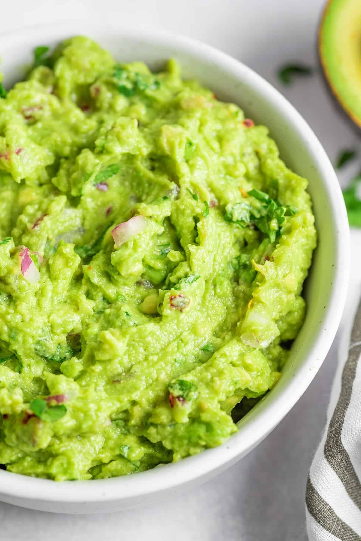 keto guacamole in a bowl with a sliced avocado