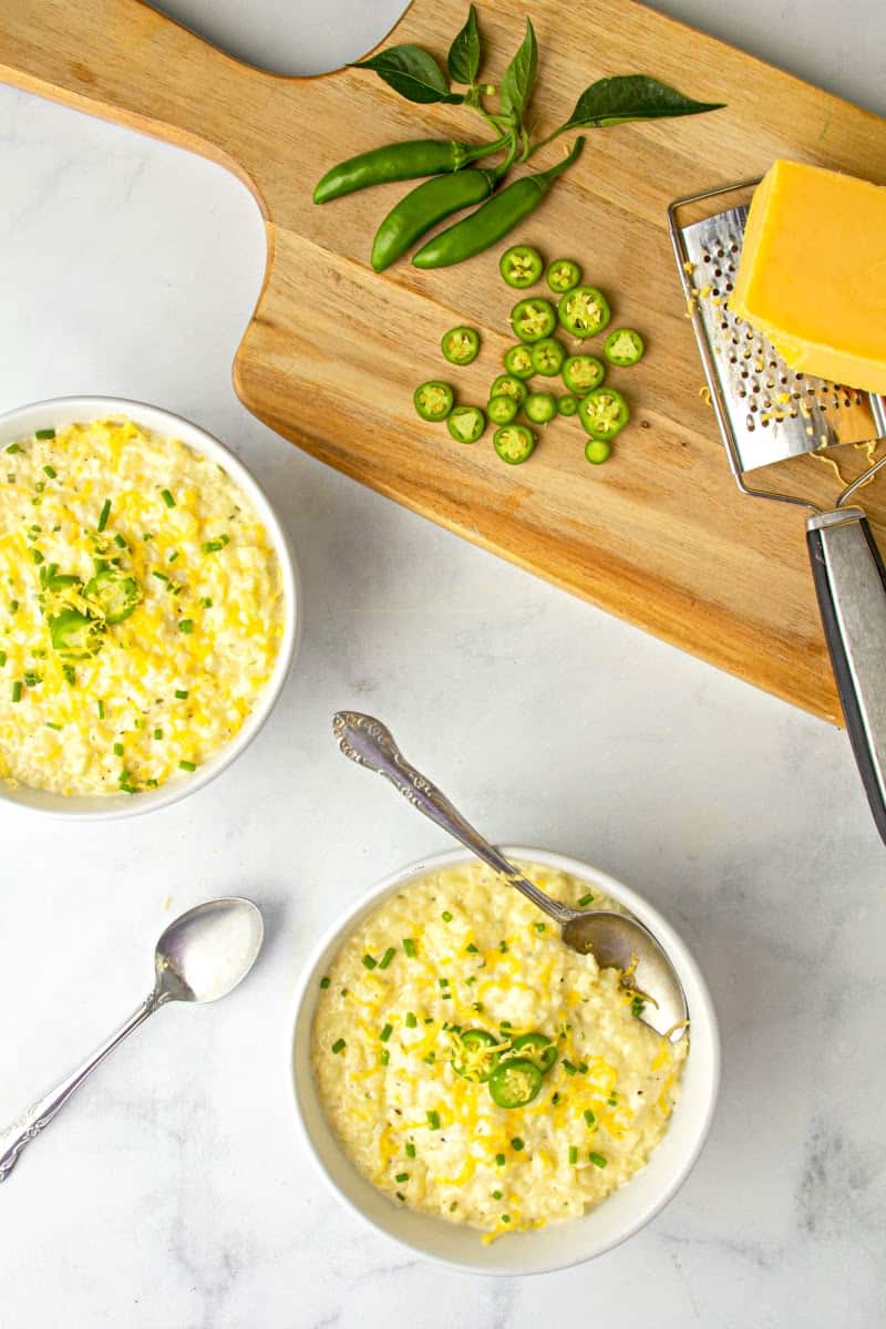 two bowls of Cheese Cauliflower Rice Grits with cheddar block