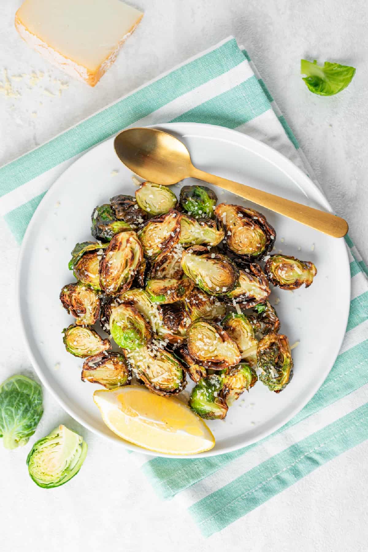 Overhead view of air fryer Brussels sprouts topped with Parmesan cheese on a plate.